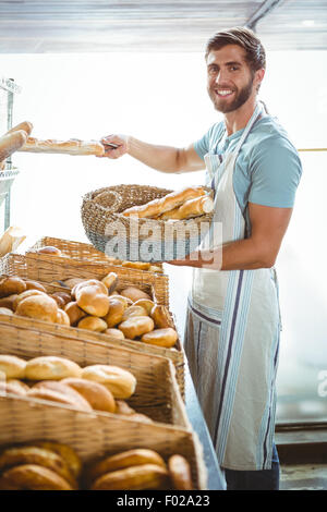 Portrait of happy worker holding basket of bread Stock Photo