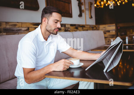 Young man having cup of coffee reading newspaper Stock Photo