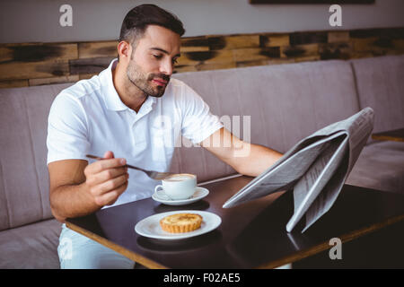 Young man having cup of coffee reading newspaper Stock Photo