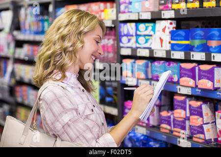 Side view of a happy smiling blonde woman writing on her notepad Stock Photo