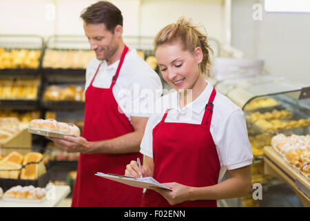 Two smiling colleagues writing on notepad Stock Photo