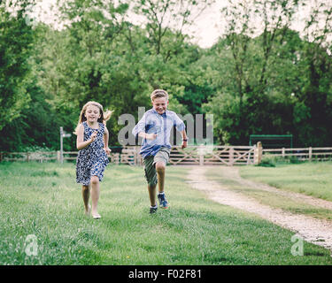 Two children racing each other in a field Stock Photo