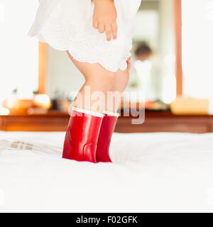 Close-up of a girl in red boots jumping on a bed Stock Photo