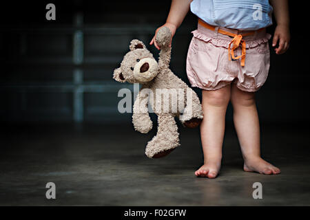 Low section of a girl holding her teddy bear Stock Photo