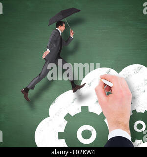 Composite image of businessman jumping holding an umbrella Stock Photo