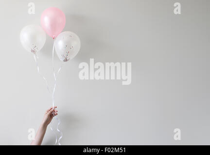 hand holding balloons with confetti inside Stock Photo