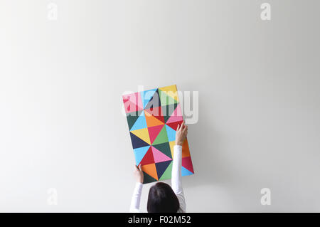 Woman decorating an empty white wall with colorful artwork Stock Photo