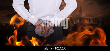 Composite image of businessman in handcuffs holding bribe Stock Photo