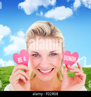 Composite image of attractive young blonde holding little hearts Stock Photo