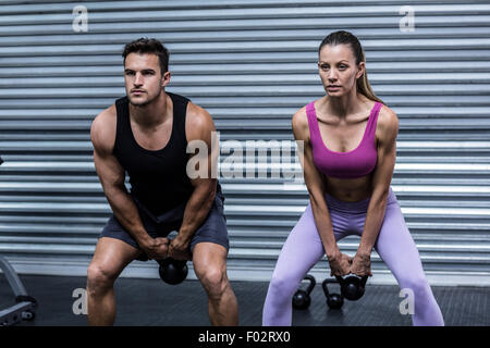 A muscular couple lifting kettlebells Stock Photo
