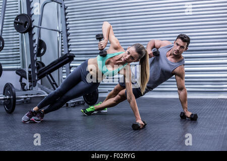 Smiling muscular couple doing side plank Stock Photo