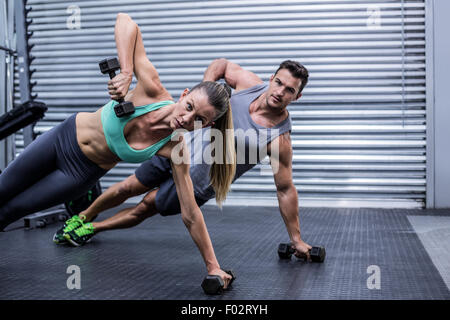 Smiling muscular couple doing side plank Stock Photo