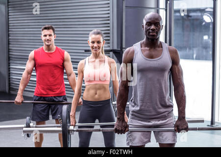 Three muscular athletes lifting barbells Stock Photo