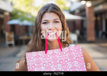 Portrait of smiling woman holding shopping bag in her mouth Stock Photo