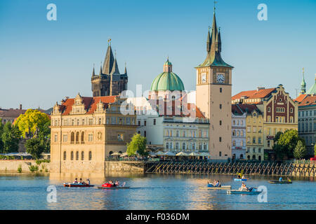 People in car-shaped paddle boats in Vltava River with Charles bridge and Novotneho lavka in background, Prague, Czech Republic Stock Photo