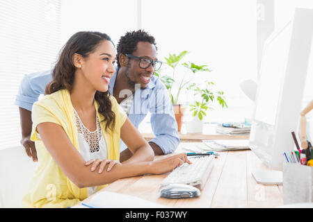Smiling colleagues working on computer Stock Photo