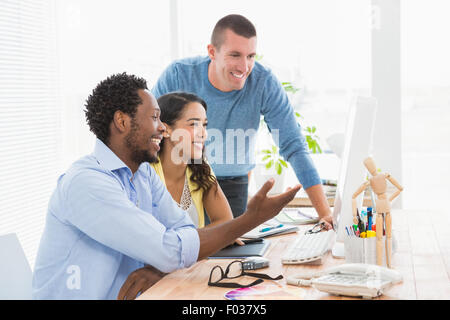 Smiling coworkers using computer together Stock Photo