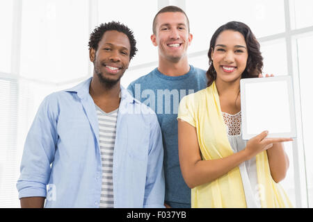 portrait of smiling colleagues presenting tablet computer and looking at camera Stock Photo