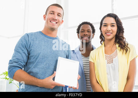 Portrait of smiling colleagues presenting tablet computer and looking at camera Stock Photo