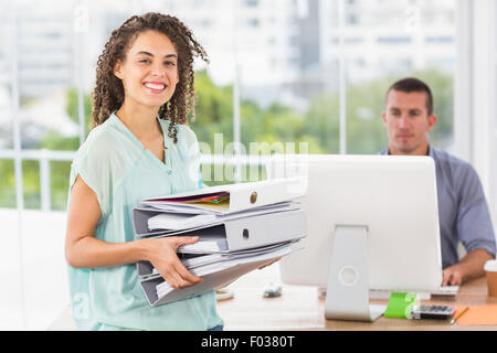 Smiling businesswoman carrying a stack of folders