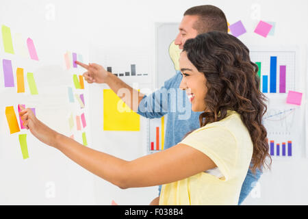 Smiling coworkers pointing sticky notes Stock Photo