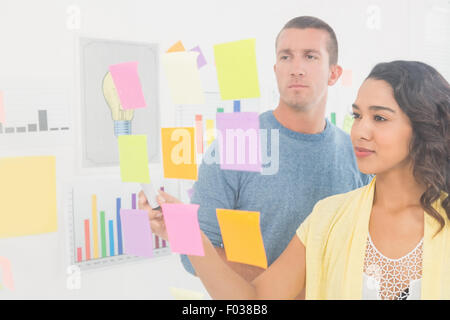 Concentrated coworkers pointing sticky notes Stock Photo