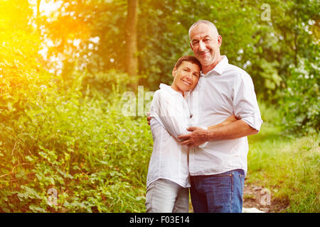 Happy smiling senior couple standing in a forest in summer Stock Photo