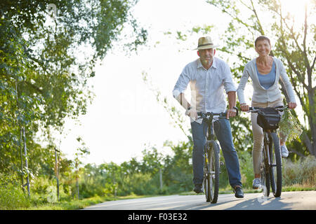 Happy senior couple riding bicycles on a bike path in summer Stock Photo