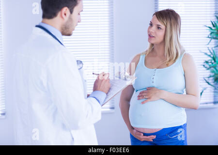 Pregnant patient talking to doctor which is taking notes Stock Photo