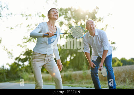 Senior couple playing badminton in summer in nature Stock Photo