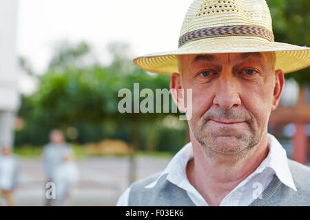 Senior man with hat looking neutral outside in a city Stock Photo