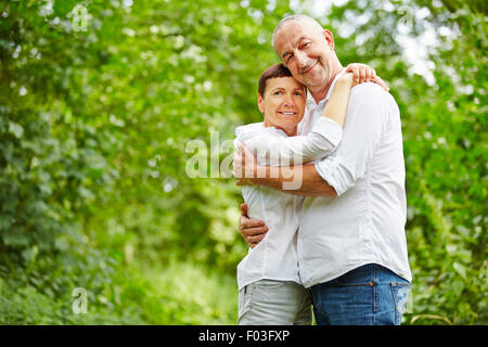 Happy senior couple embracing in a forest in summer Stock Photo