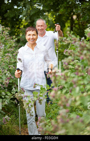 Happy senior couple doing nordic walking in a forest Stock Photo