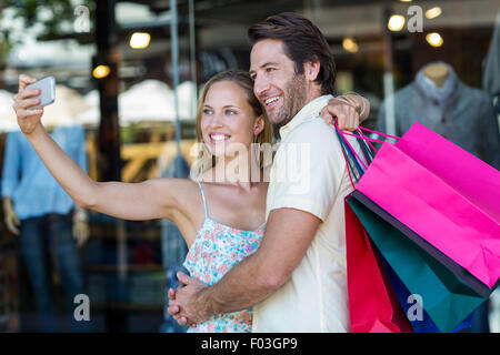 Smiling couple embracing and taking selfies Stock Photo