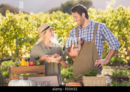 Smiling farmer couple holding chicken and eggs Stock Photo