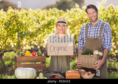 Farmer couple holding a basket and organic sign Stock Photo