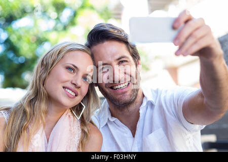 Smiling couple sitting and taking selfies Stock Photo