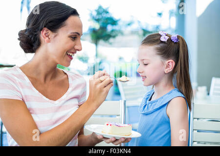 Mother feeding her daughter with cake Stock Photo