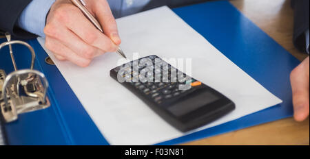 Businessman using a calculator and writing Stock Photo