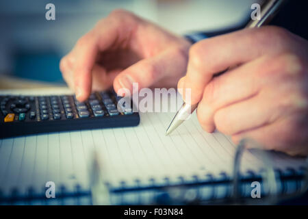Businessman using a calculator and writing Stock Photo