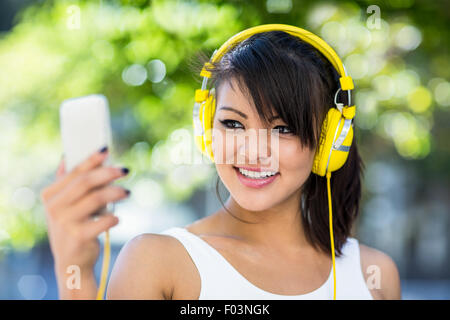 Smiling athletic woman wearing yellow headphones and taking selfies Stock Photo