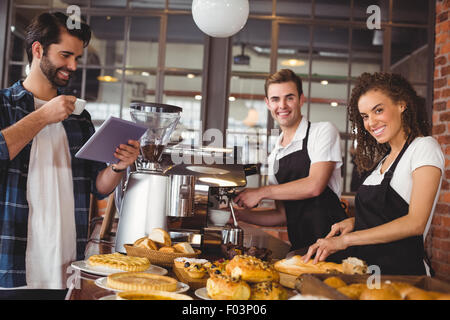 Smiling colleagues serving customer with tablet and coffee Stock Photo