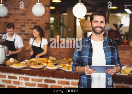 Smiling hipster using tablet in front of working barista Stock Photo