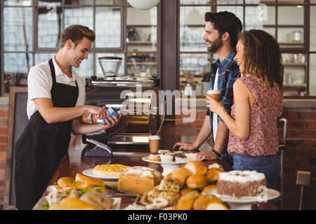 Smiling barista taking credit card from hipsters Stock Photo