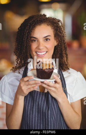 A young retail employee with curly hair holds cardboard boxes in a