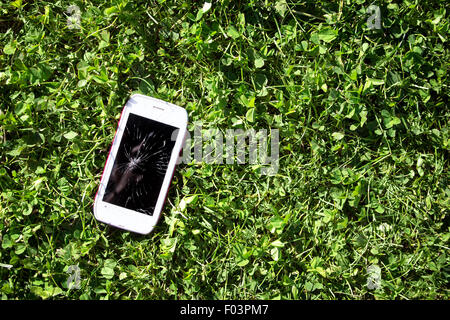 Smartphone with broken screen lying on the grass Stock Photo