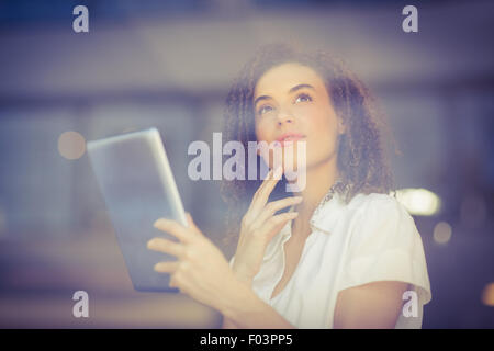 Thoughtful woman using a digital tablet Stock Photo