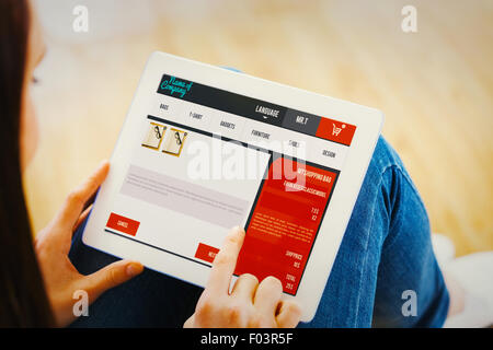 Composite image of teen using a tablet pc sitting on the floor Stock Photo