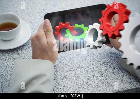 Composite image of businessman holding small tablet at table Stock Photo