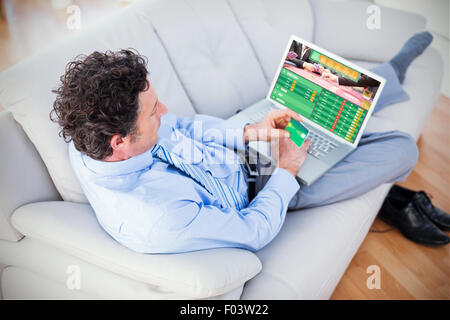 Composite image of businessman doing online shopping on couch Stock Photo